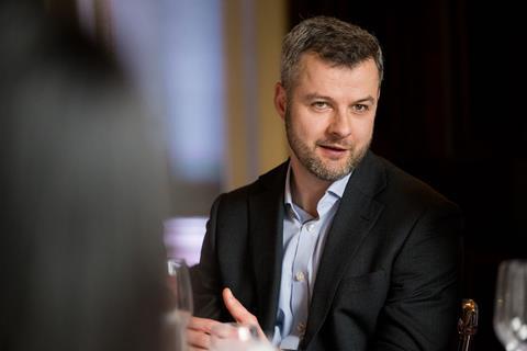 Photograph of Insurance Fraud Enforcement Dept. City of London Police detective inspector Tom Hill. He wears a blue pinstriped shirt with a black blazer over the top.